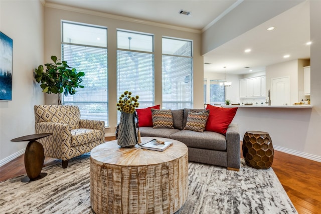 living room with crown molding, light hardwood / wood-style flooring, and a notable chandelier