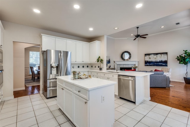 kitchen with sink, light tile patterned flooring, kitchen peninsula, and appliances with stainless steel finishes