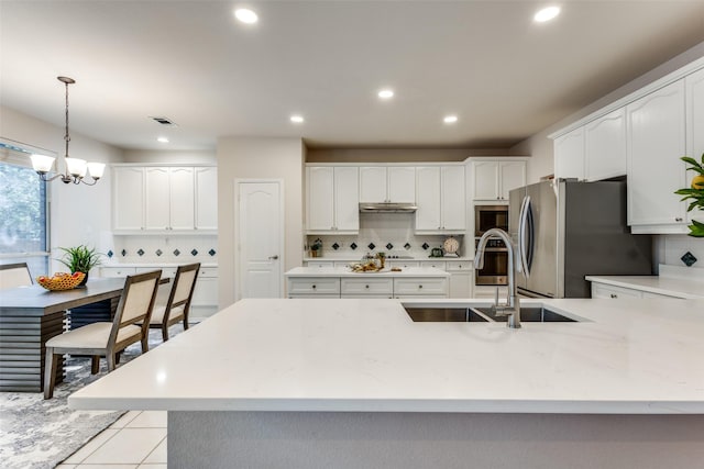 kitchen with sink, light tile patterned floors, stainless steel fridge, hanging light fixtures, and tasteful backsplash