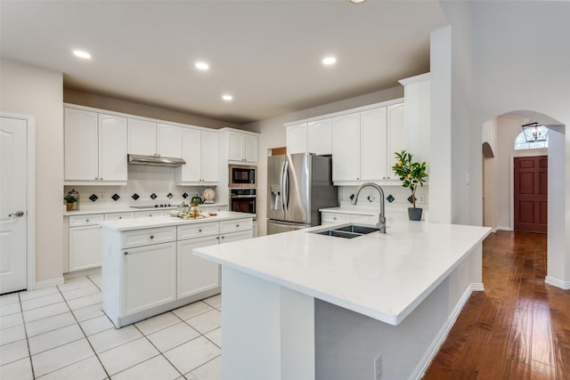 kitchen featuring sink, tasteful backsplash, appliances with stainless steel finishes, kitchen peninsula, and white cabinets