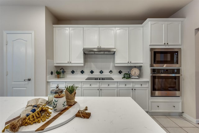 kitchen with tasteful backsplash, stainless steel appliances, light tile patterned floors, and white cabinets