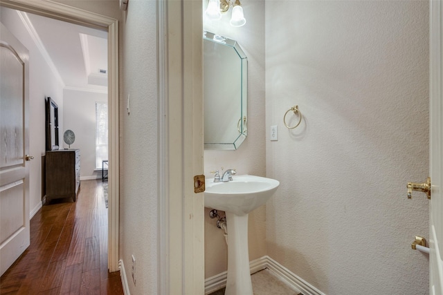 bathroom with hardwood / wood-style floors, crown molding, and sink