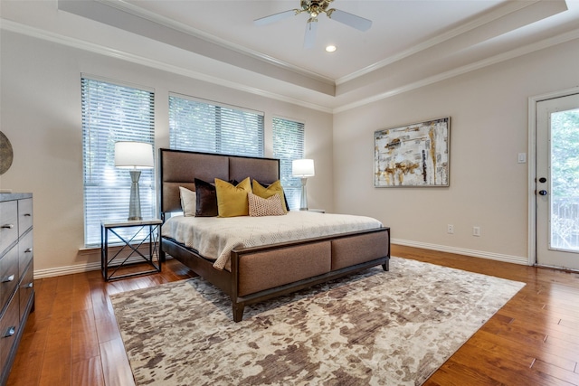 bedroom featuring ceiling fan, a tray ceiling, ornamental molding, dark hardwood / wood-style flooring, and access to outside