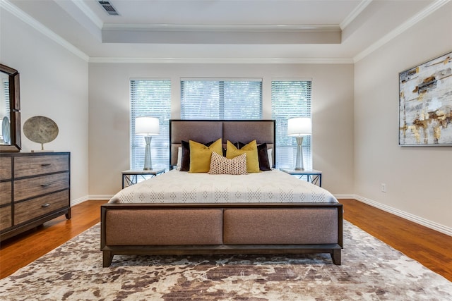 bedroom with multiple windows, a tray ceiling, and wood-type flooring