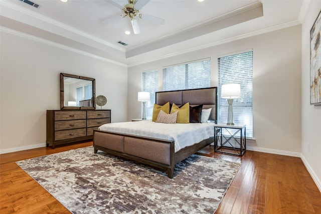 bedroom featuring crown molding, hardwood / wood-style floors, a tray ceiling, and ceiling fan