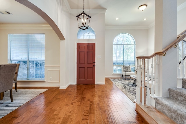 foyer entrance with crown molding, hardwood / wood-style floors, and a notable chandelier