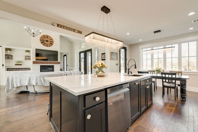 kitchen with pendant lighting, a notable chandelier, an island with sink, and dishwasher