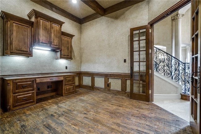 kitchen with beam ceiling, dark brown cabinets, built in desk, and french doors