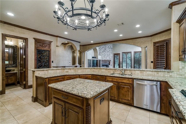 kitchen with stainless steel dishwasher, decorative backsplash, decorative light fixtures, a kitchen island, and decorative columns