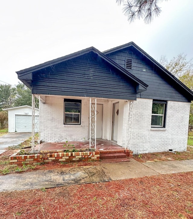 bungalow-style home with a porch, an outdoor structure, and a garage