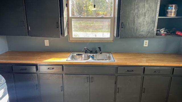 kitchen featuring gray cabinetry, sink, and wood counters