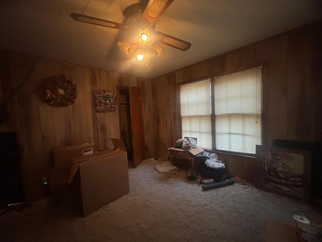 misc room featuring carpet flooring, ceiling fan, and wooden walls