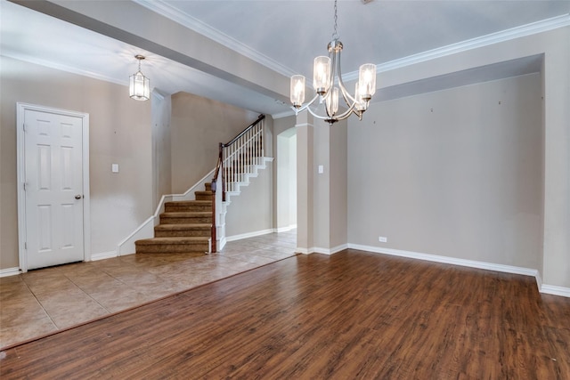 spare room featuring crown molding, wood-type flooring, and a chandelier