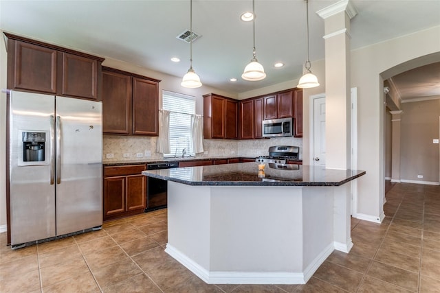 kitchen featuring dark stone countertops, appliances with stainless steel finishes, tasteful backsplash, decorative light fixtures, and a kitchen island