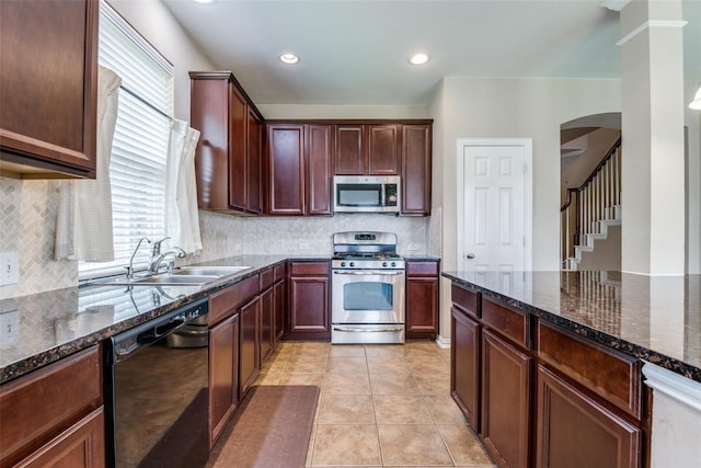 kitchen with sink, dark stone counters, decorative backsplash, light tile patterned floors, and appliances with stainless steel finishes