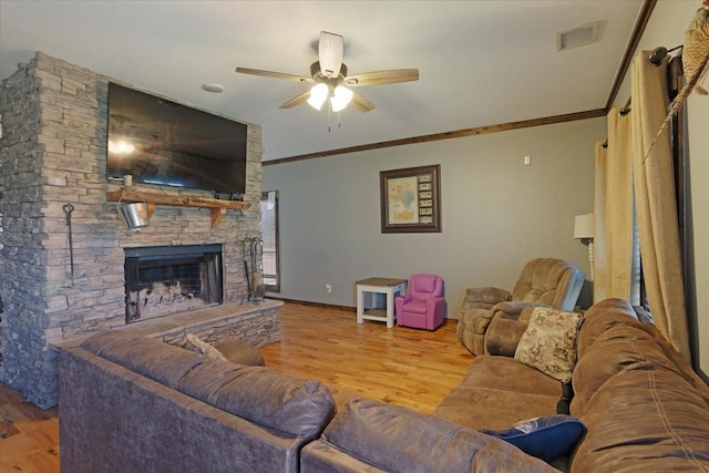 living room featuring ornamental molding, ceiling fan, a fireplace, and light hardwood / wood-style flooring