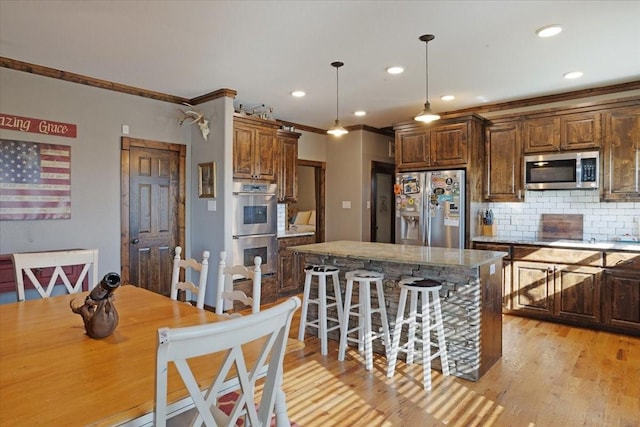 kitchen featuring tasteful backsplash, a center island, light wood-type flooring, pendant lighting, and stainless steel appliances