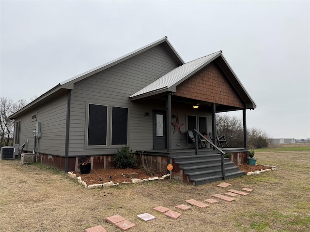 view of front of home with cooling unit, a front lawn, and a porch