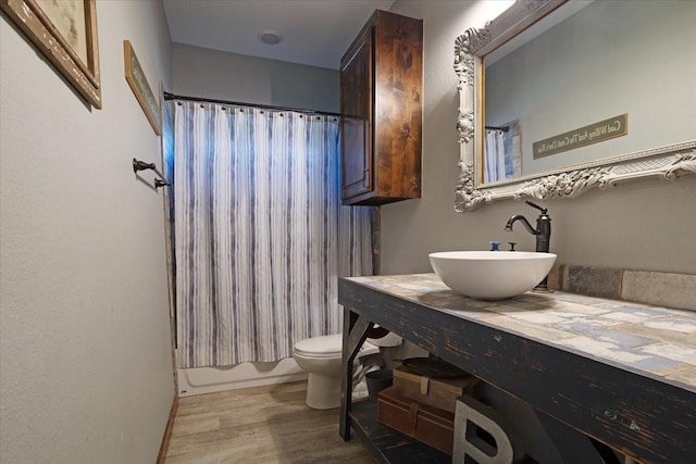 full bathroom featuring sink, wood-type flooring, toilet, and shower / bath combo with shower curtain