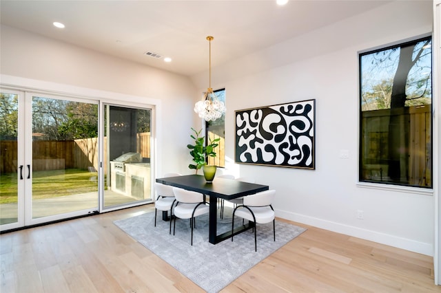 dining area with light wood-type flooring and a notable chandelier