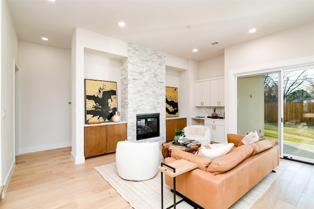 living room with light hardwood / wood-style flooring and a stone fireplace