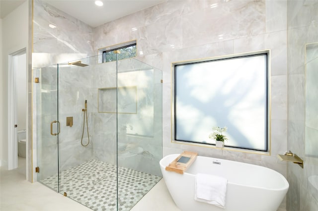 bathroom with tile walls and independent shower and bath