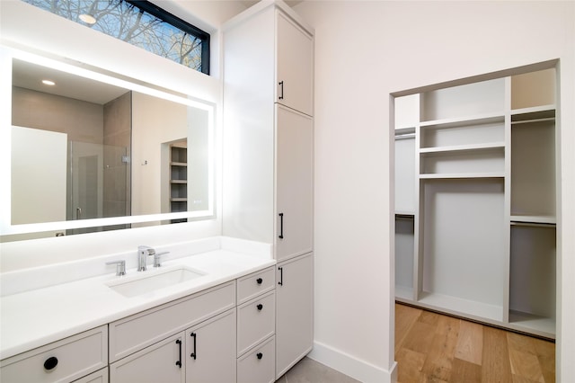 bathroom featuring wood-type flooring, a shower with shower door, and vanity