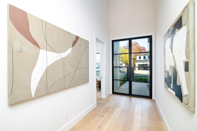 entryway with french doors, a towering ceiling, and light hardwood / wood-style flooring