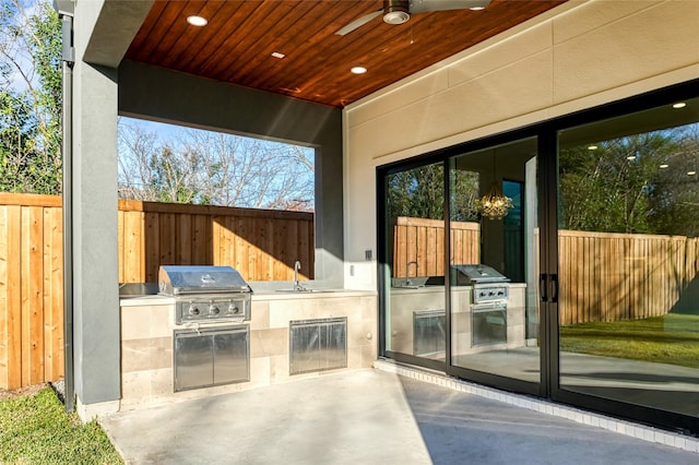 view of patio featuring a grill, ceiling fan, sink, and exterior kitchen