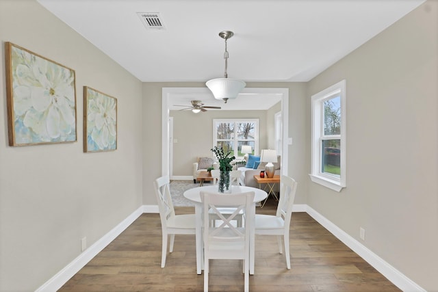 dining space with ceiling fan and dark wood-type flooring