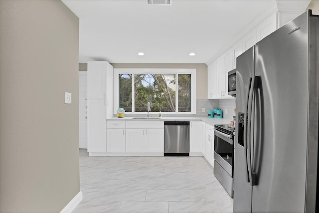 kitchen featuring white cabinets, appliances with stainless steel finishes, backsplash, and sink