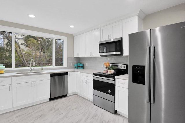 kitchen featuring white cabinets, decorative backsplash, stainless steel appliances, and sink