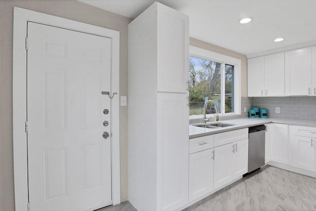 kitchen with tasteful backsplash, sink, white cabinets, and stainless steel dishwasher