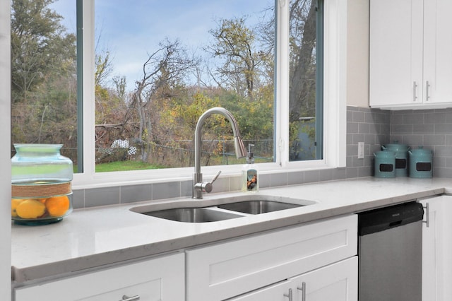 kitchen featuring dishwasher, white cabinets, sink, decorative backsplash, and light stone countertops