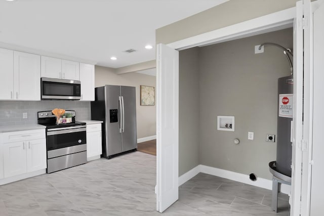 kitchen with tasteful backsplash, white cabinets, and appliances with stainless steel finishes