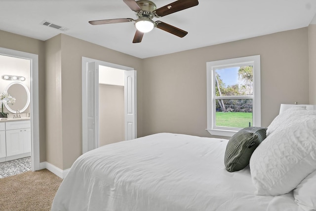 bedroom with ensuite bath, ceiling fan, and light colored carpet