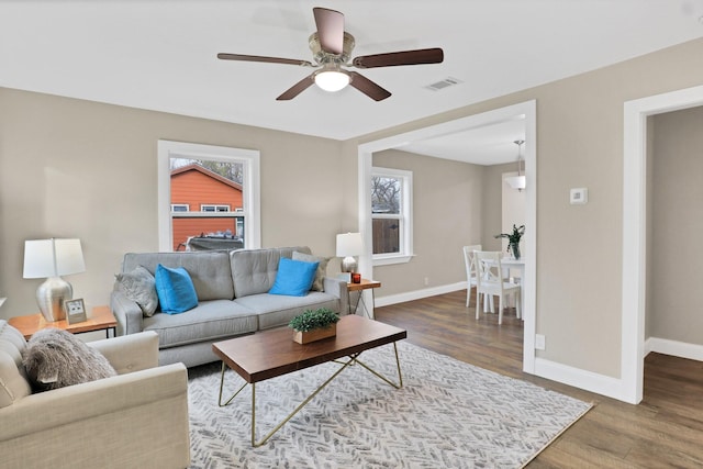 living room featuring ceiling fan and dark wood-type flooring