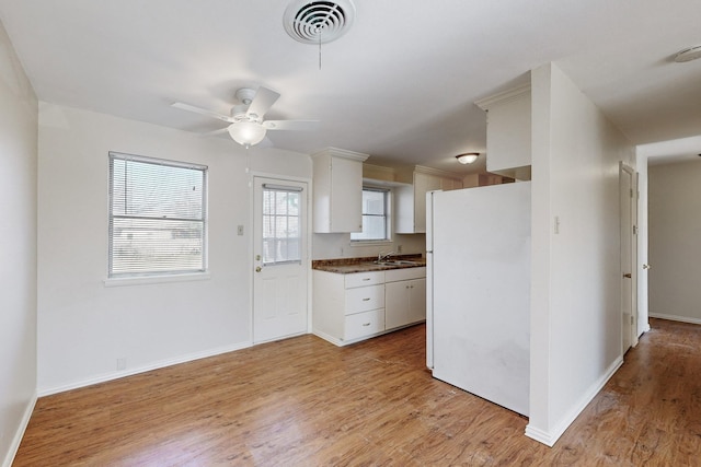 kitchen featuring white cabinets, white refrigerator, light wood-type flooring, and ceiling fan