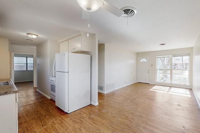 kitchen with white appliances, plenty of natural light, and light hardwood / wood-style flooring