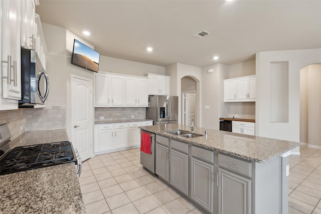 kitchen featuring appliances with stainless steel finishes, tasteful backsplash, white cabinetry, and a kitchen island with sink