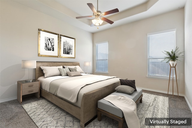 bedroom with carpet floors, a raised ceiling, and ceiling fan