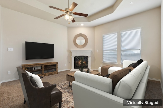 carpeted living room with a tray ceiling and ceiling fan