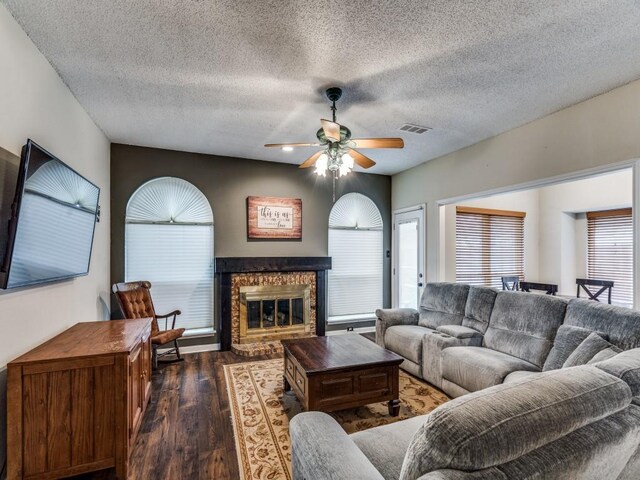 living room with ceiling fan, dark hardwood / wood-style flooring, and a textured ceiling