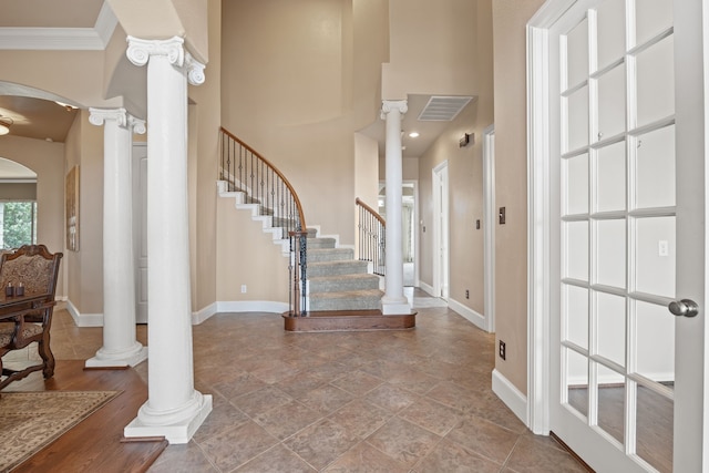 entrance foyer with ornate columns, crown molding, and a high ceiling