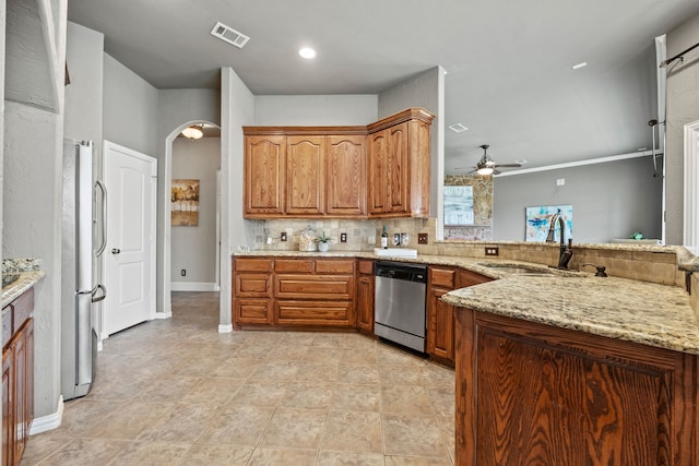 kitchen featuring backsplash, sink, ceiling fan, appliances with stainless steel finishes, and light stone counters