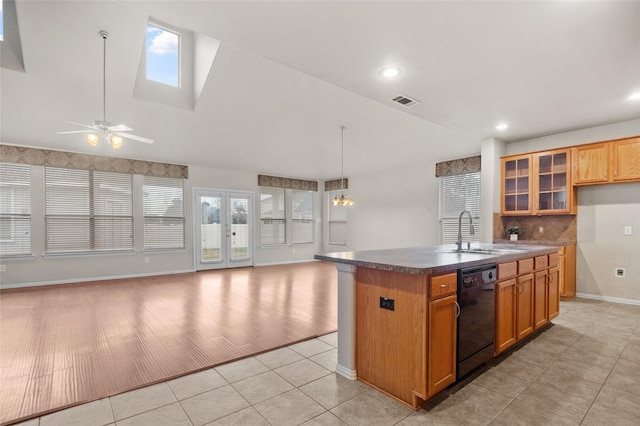 kitchen with lofted ceiling with skylight, sink, light tile patterned floors, dishwasher, and an island with sink