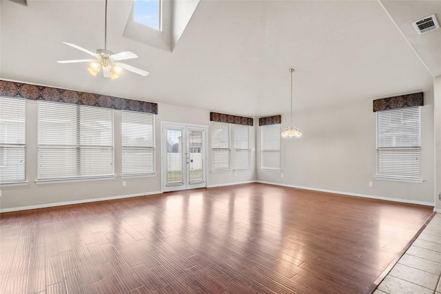 unfurnished living room with ceiling fan with notable chandelier and high vaulted ceiling