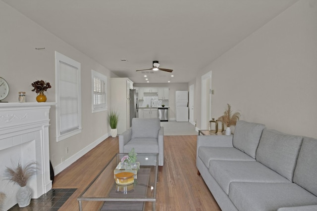 living room featuring ceiling fan, a fireplace, dark wood-style flooring, and baseboards