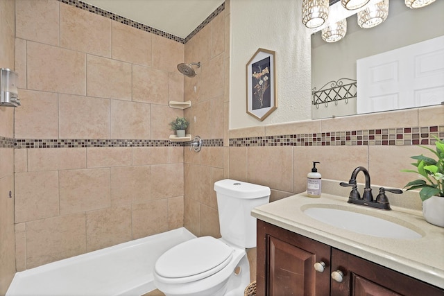 bathroom with tiled shower, toilet, tile walls, and vanity