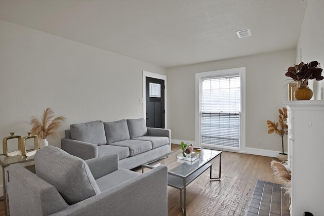 living area with visible vents, baseboards, and wood finished floors